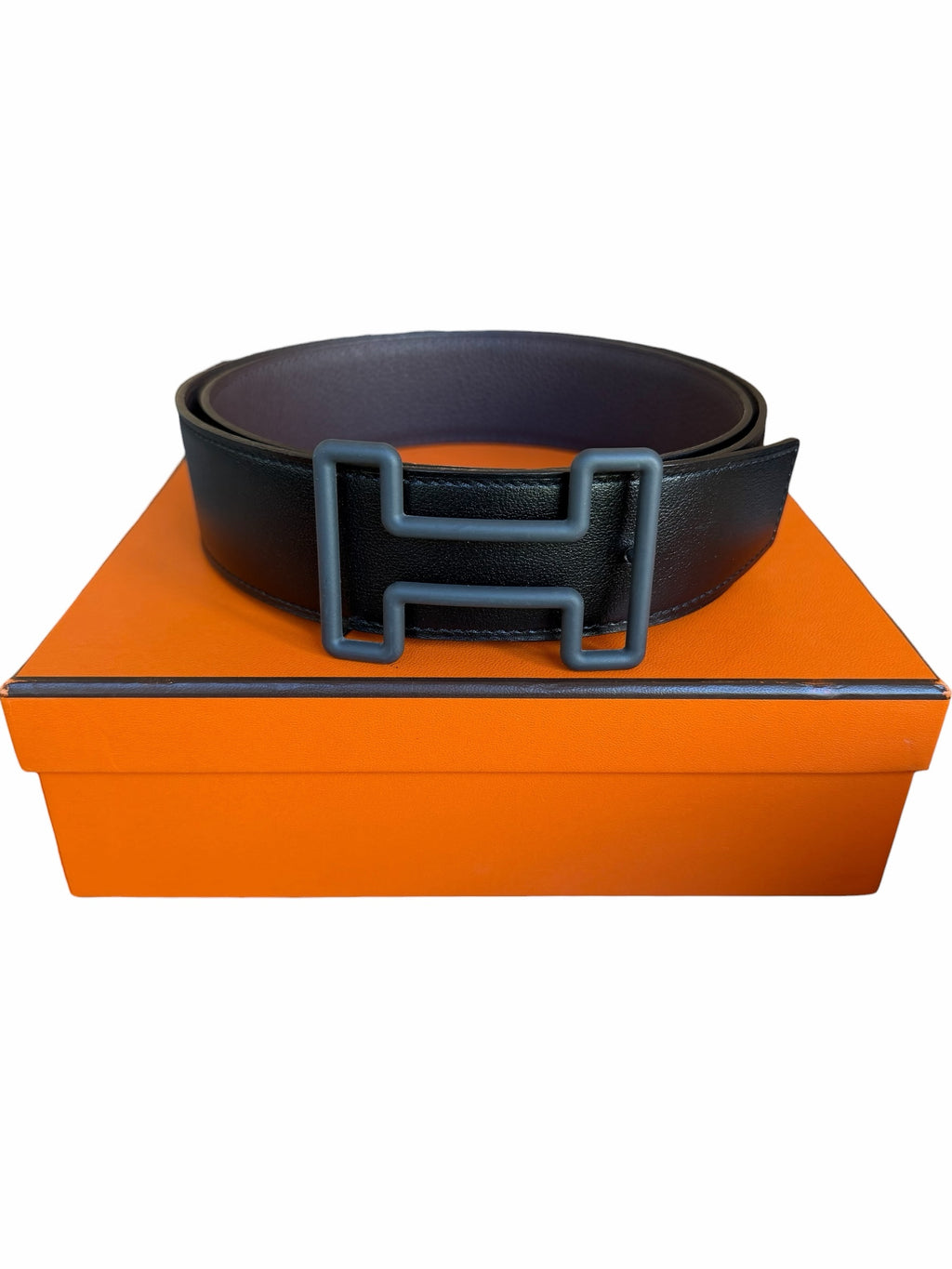 Studio444 HERMÈS black leather belt with a matte H-shaped buckle resting on an orange luxury gift box